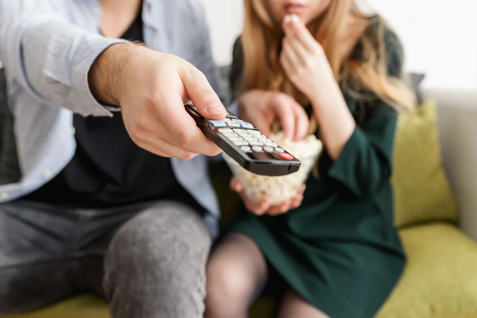 Casal maratonando séries em IPTV no sofá com controle remoto e pipoca